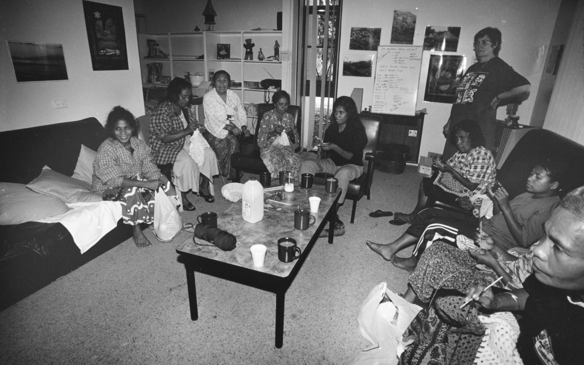 Group of men and women from East Timor sitting on couches around a coffee table crocheting