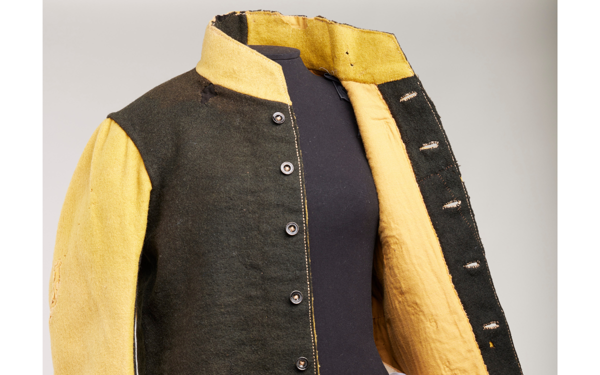 Black and yellow uniform made up of a long-sleeve button up jacket on a mannequin