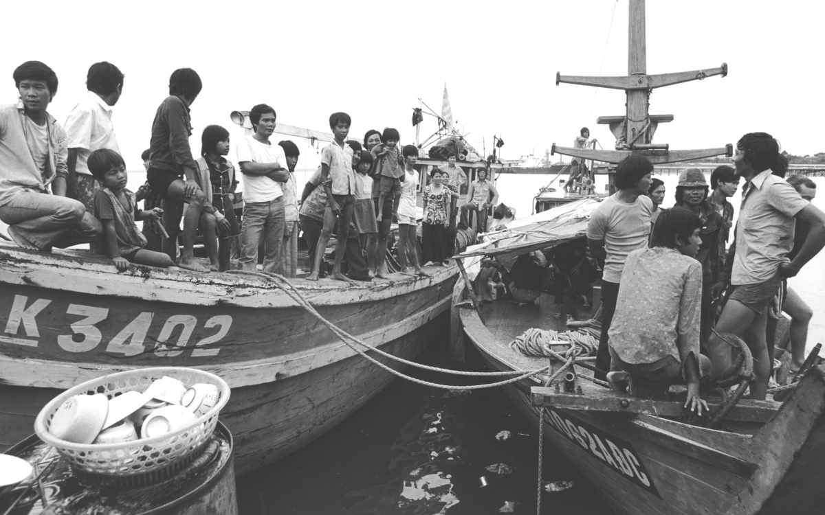Two boats with rope hanging between them filled with men, women and children coming from Vietnam