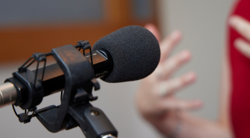 Microphone on a stand pointed towards a person speaking