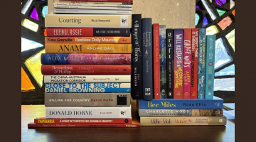 A stack of books in front of stained glass windows.