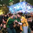 Two woman in green and gold clothing embracing excitedly in front of a crowd.