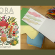 The book cover of 'Flora' by Tania McCartney and a sketchbook with colouring pencils.