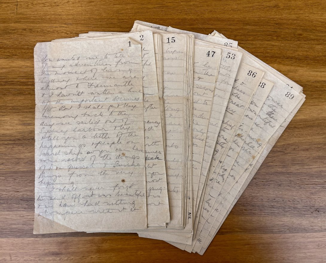 Small spread of handwritten letters, with each page numbered 1 to 100 in the top right corner, on a wooden surface