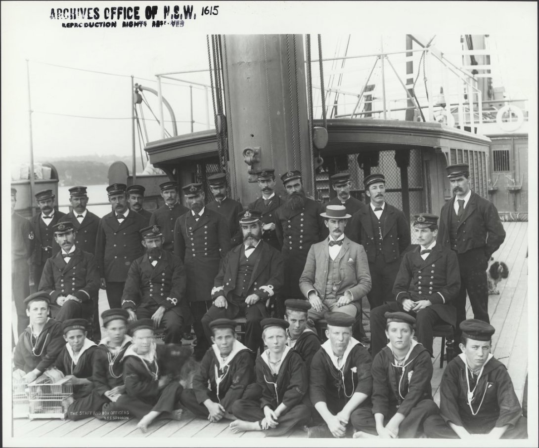 Captain Neitenstein and other male crew/staff of the Sobraon in uniforms and a small group of students sitting on the deck